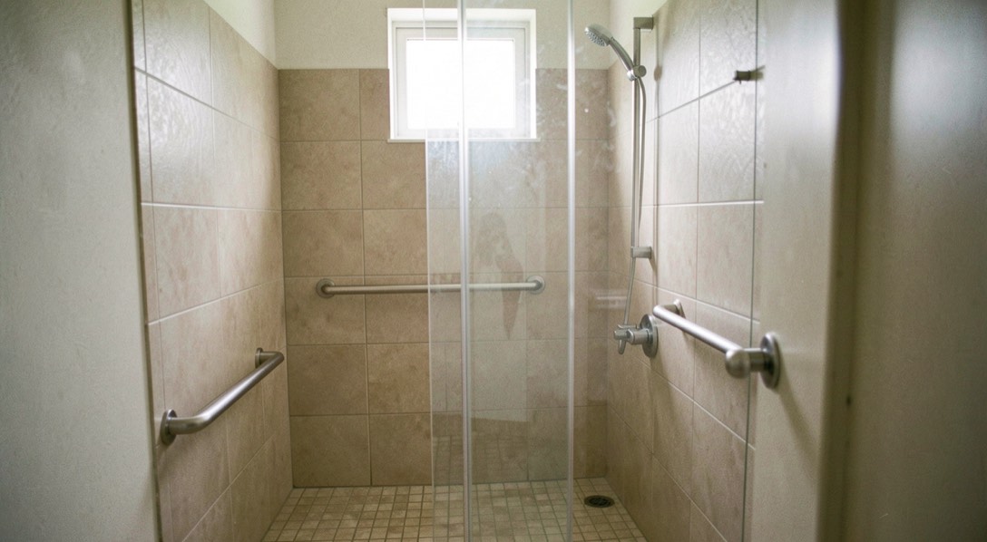 Une salle de bain claire avec une douche de plain-pied aux carreaux beiges, une barre d